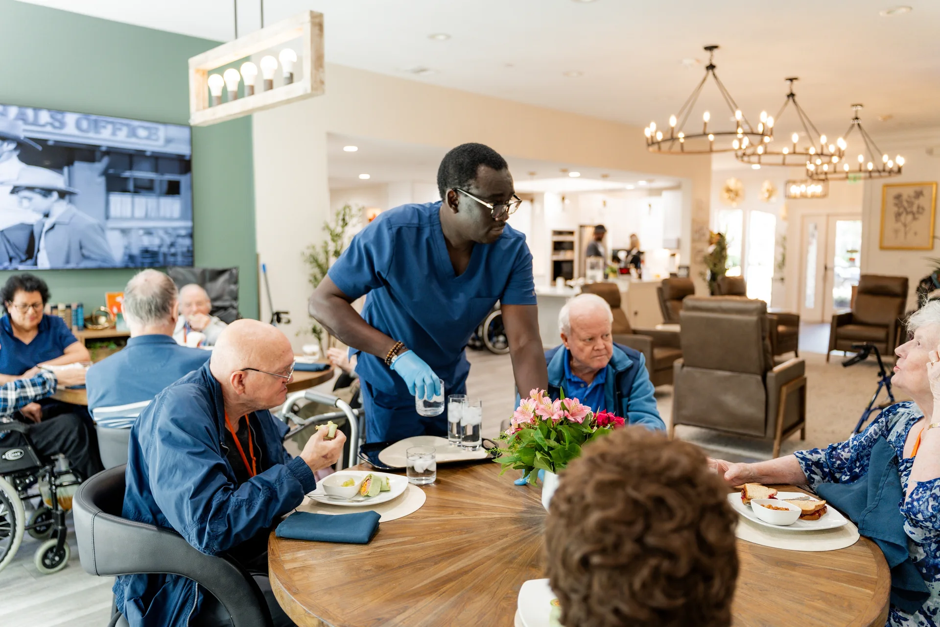 A caregiver pouring a drink for a resident at the table
