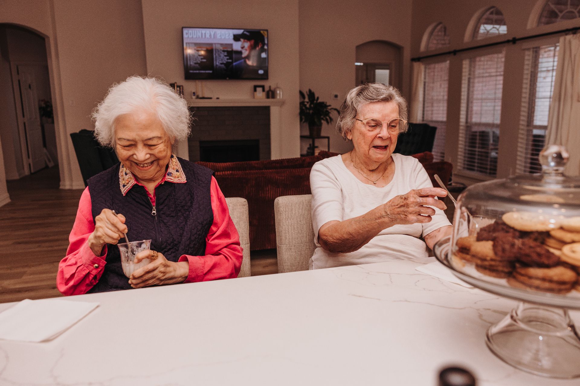 Two residents sharing refreshments at the kitchen island